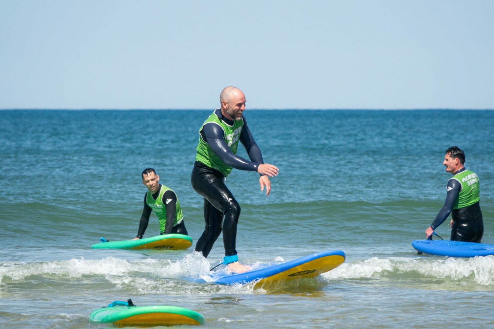trois hommes apprennent à faire du surf à Lacanau